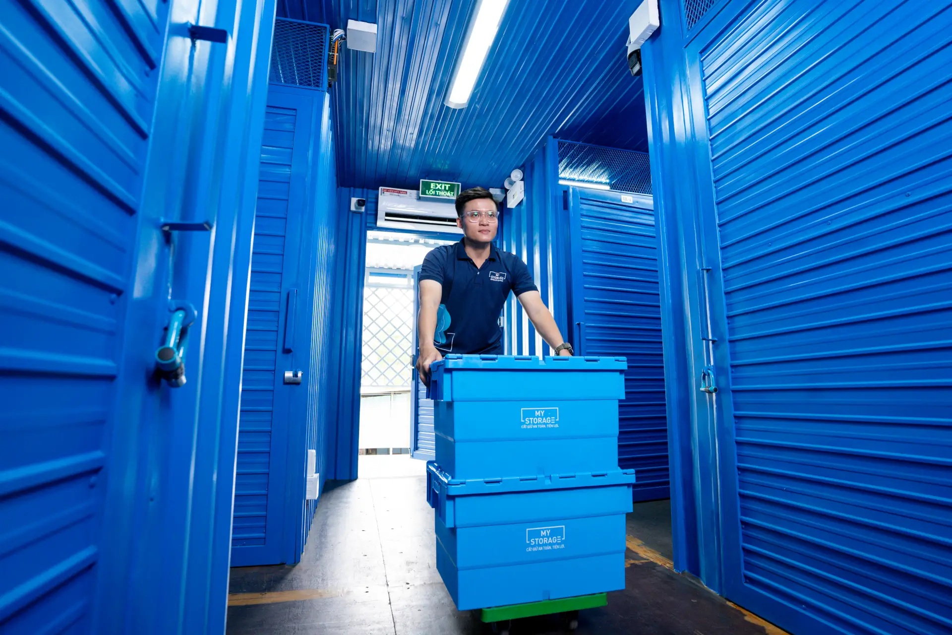 A man moving blue storage boxes at the MyStorage facility.