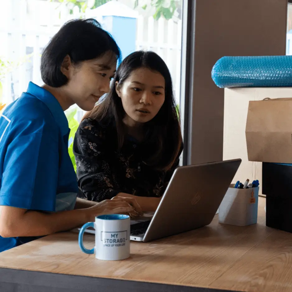 Two colleagues reviewing document storage options on a laptop.