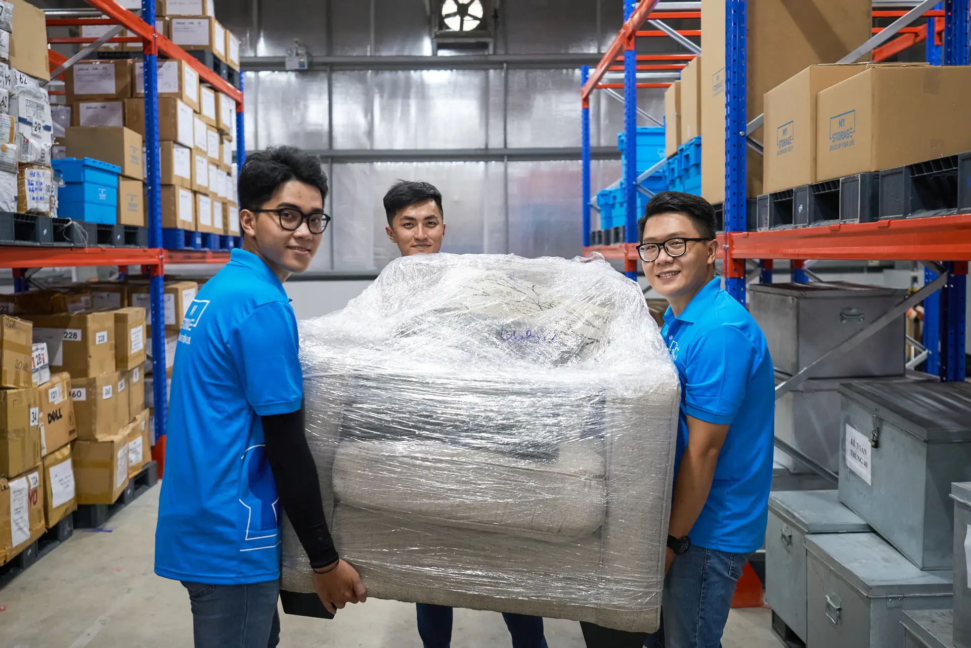 Three MyStorage workers carrying wrapped furniture